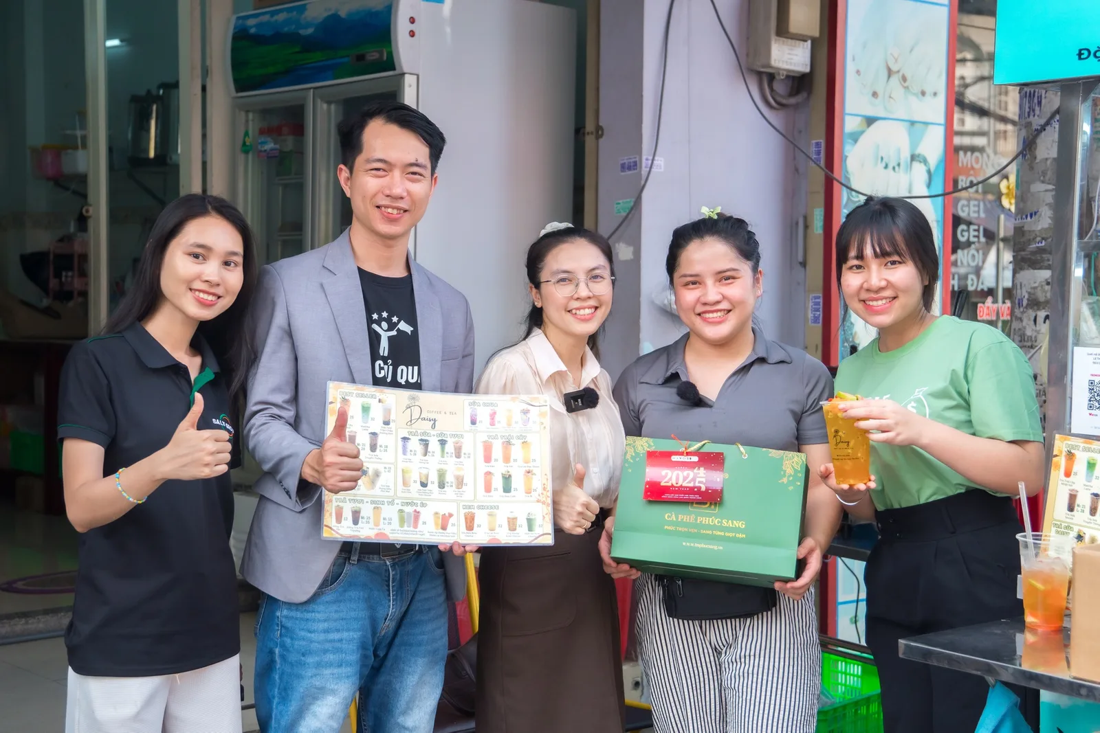 Đội ngũ học viện đến thăm quán của học viên, trao giáo trình và quà tặng trước quầy pha chế
